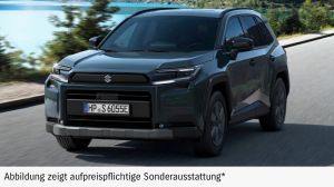 Dunkler Suzuki Across auf einem Parkplatz mit Bäumen im Hintergrund. 