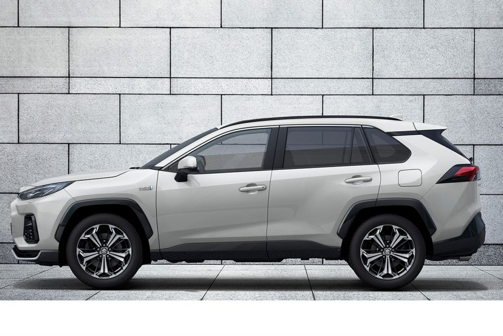 Weißer Suzuki Across in Seitenansicht vor einer grauen Steinwand.