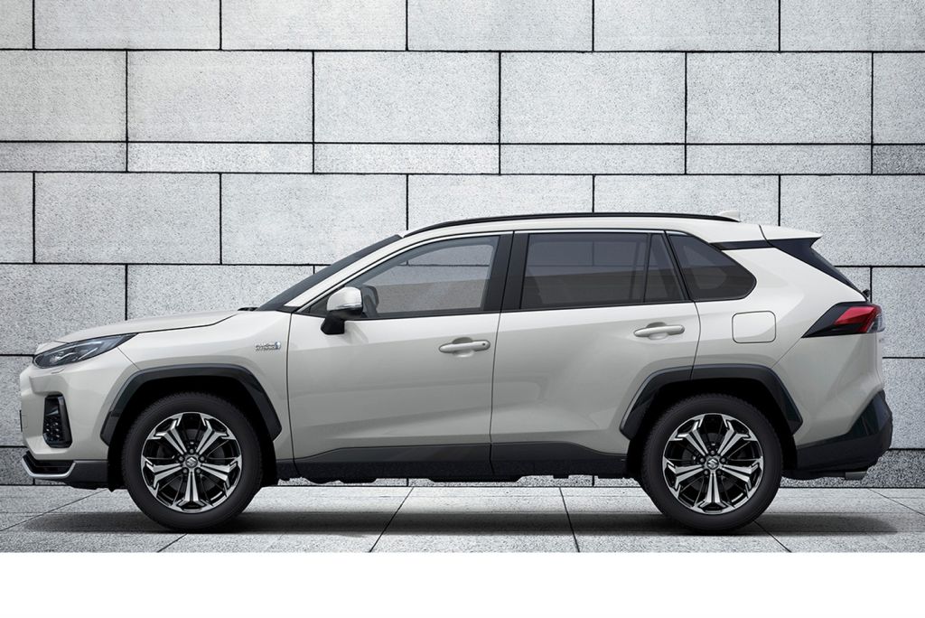 Weißer Suzuki Across in Seitenansicht vor einer grauen Steinwand.