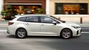 Weißer Suzuki Swace Hybrid in Seitenansicht vor City-Setting