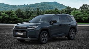 Weißer Suzuki Across Hybrid in Seitenansicht vor City-Setting und Betonwand