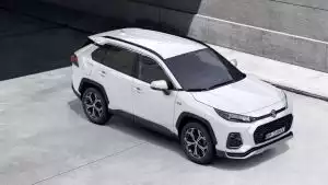 Weißer Suzuki Across Hybrid in Seitenansicht vor City-Setting und Betonwand