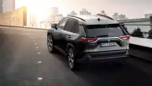 Schwarzer Suzuki Across Hybrid auf Brücke vor City-Setting und Sonnenuntergang