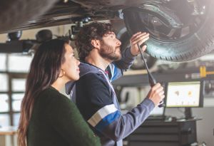 Mechanikerin und Mechaniker arbeiten am Unterboden eines Fahrzeugs
