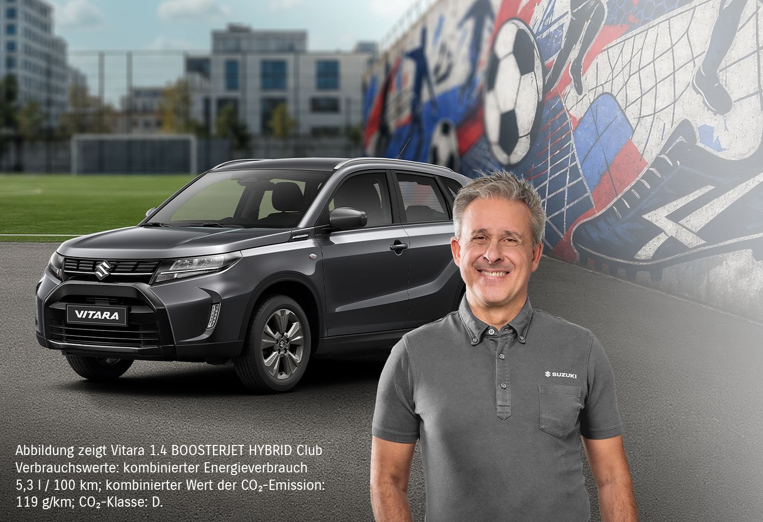 Blauer Suzuki Vitara vor einem Fußballplatz, daneben ein lächelnder Mann mittleren Alters im grauen Suzuki-Poloshirt, im Hintergrund eine bunte Wand mit Fußball-Graffiti und Sportschuh-Motiv.