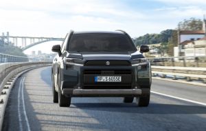 Weißer Suzuki Across PLUG-IN HYBRID Comfort+ bei Fahrt über Brücke in Front-Seitenansicht