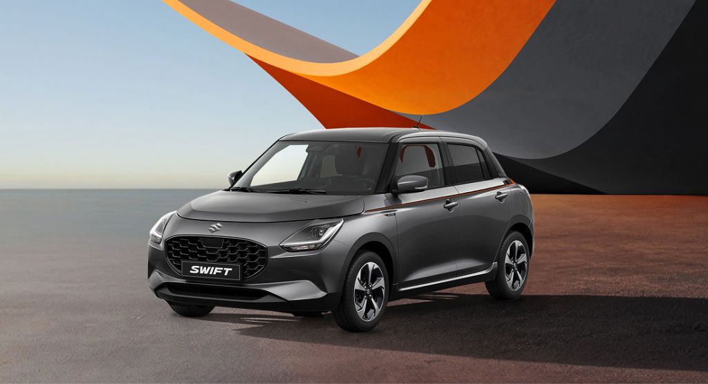 Suzuki Swift X-ITE in grauer Lackierung, schräg von vorne vor stilisiertem Hintergrund.