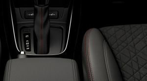 Innenraumdetail des Suzuki Vitara X-ITE mit orangefarbenen Ziernähten an Sitzen und an der Schalthebelmanschette.