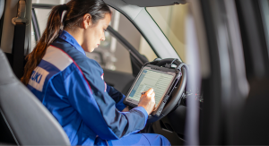 Eine Suzuki Mitarbeiterin sitzt in einem Suzuki Overall in einem Auto. Sie arbeitet an einer auf einem Tablett dargestellten Checkliste.