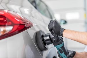 Person poliert Lackfläche mit einer Poliermaschine