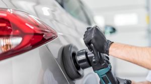 Person poliert Lackfläche mit Hilfe einer Poliermaschine